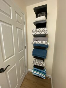 vertical shelf storing towels behind a door