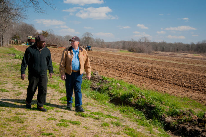 Charlie Williams (left), United States Department of Agriculture, Arkansas Strike Team Leader and Bill Hess walk along a side a pasture sharing a conversation