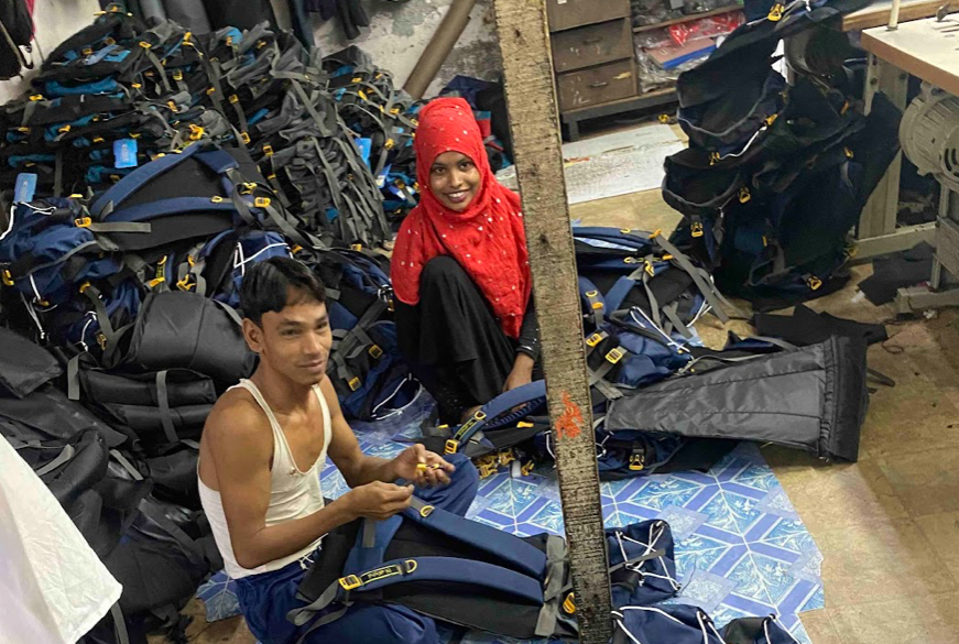 slums; All in a day's work. Workers in Dharavi's garment district pose for photo as they construct knockoff apparel and accessories. Credit: Jeffrey Andreoni