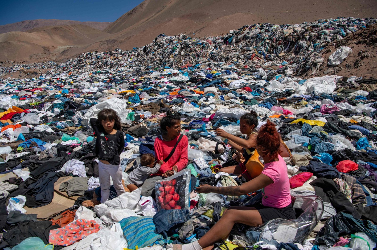 Women from <span style="font-weight: 400;">Alto Hospicio</span> search for salvageable used clothing amid the piles of waste. Credit: Agence France-Presse