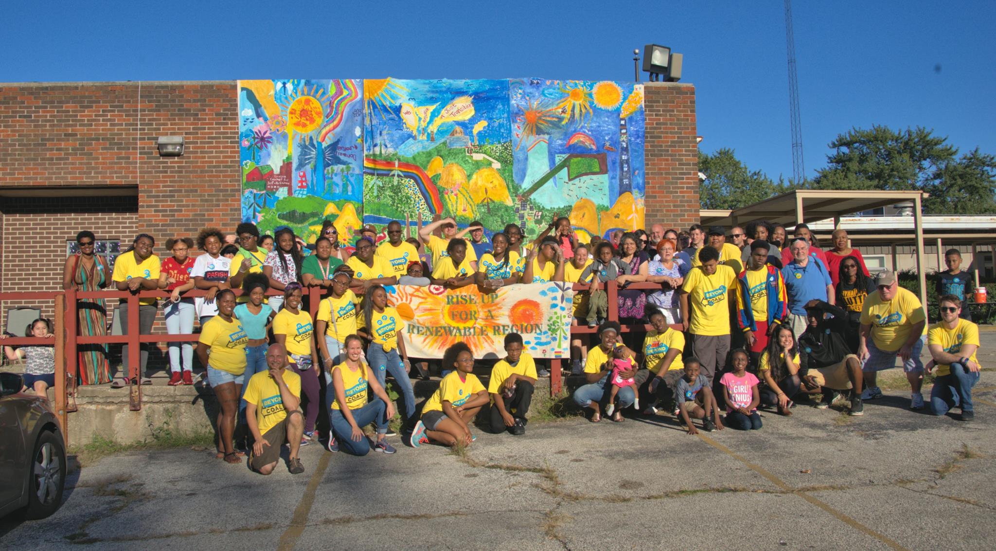 Credit: Hagelberg and Gary community members pose in front of a mural created as part of Calumet Artist Residency's "Beyond Coal" renewable energy campaign. Credit: Calumet Artist Residency